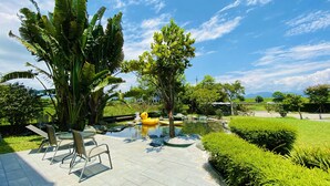 A patio area with a small pond, seating, and lush greenery.