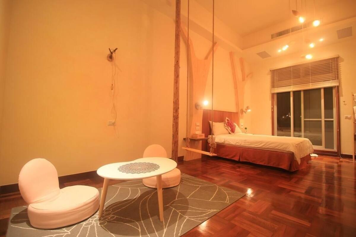 A modern hotel room with a bed, a small round table, and two chairs.