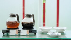 A coffee station with two coffee makers and a sign indicating the type of coffee.