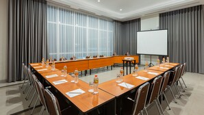 A conference room with a long table, chairs, a projector screen, and a whiteboard. - Amaris Hotel Slipi (Jakarta)