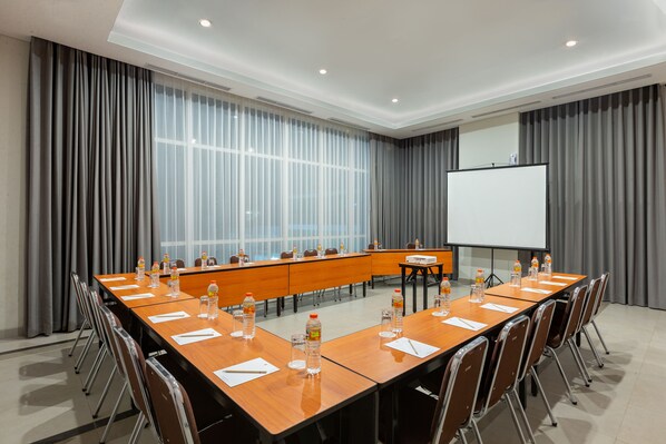 A conference room with a long table, chairs, a projector screen, and a whiteboard. - Amaris Hotel Slipi (Jakarta)