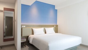 A modern hotel room with a large bed, a nightstand, a mirror, and a wall with a blue gradient design. - Amaris Hotel Slipi (Jakarta)