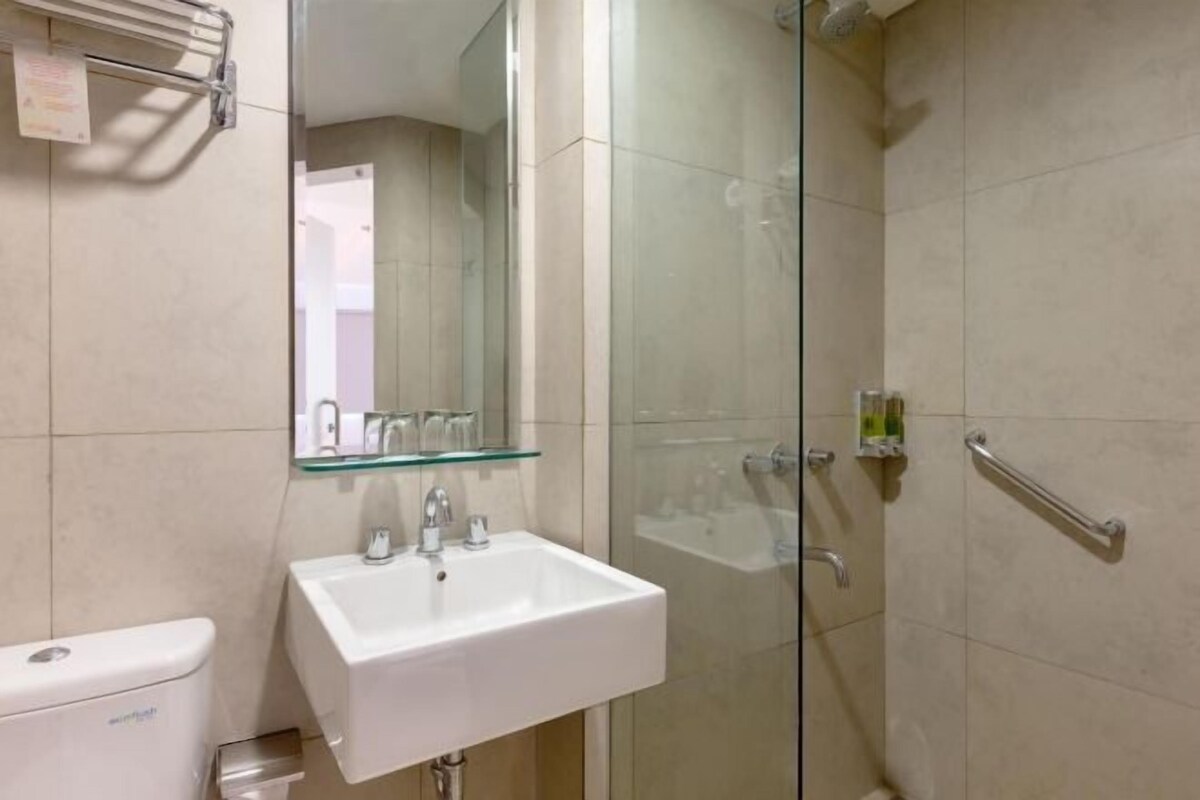 A modern bathroom with a glass shower enclosure, a white sink, and a toilet.