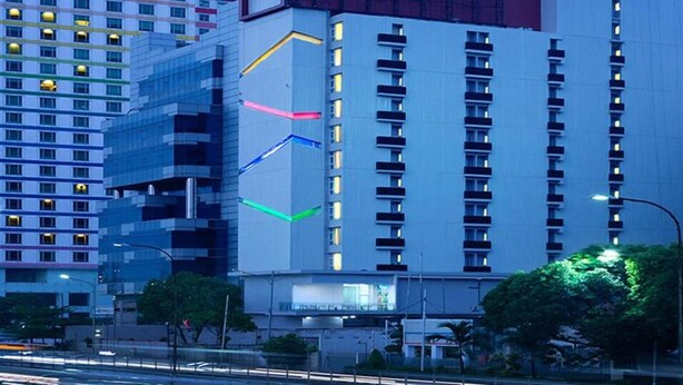 A multi-story building with a modern architectural design, featuring a prominent vertical light strip and a series of balconies. - Amaris Hotel Slipi (Jakarta)