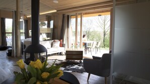 Un salon moderne doté d’une cheminée, d’un canapé, d’un coin repas et de grandes fenêtres.