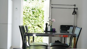 A modern dining area with a glass table, two chairs, a laptop, and a vase with flowers. - Stay Home Villa (Rødovre)