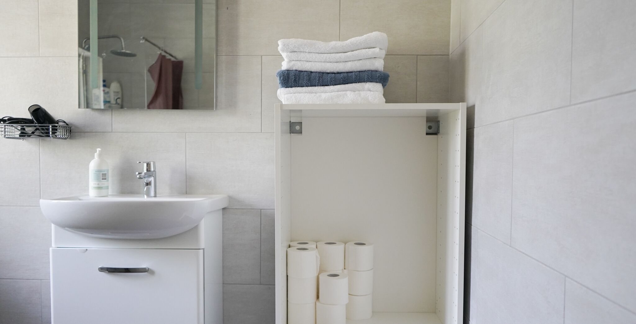 Ein modernes Badezimmer mit Waschbecken, Spiegel und Duschkabine.