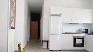 A modern kitchen with white cabinets, a microwave, a stove, and a refrigerator. - Stay Home Villa (Rødovre)