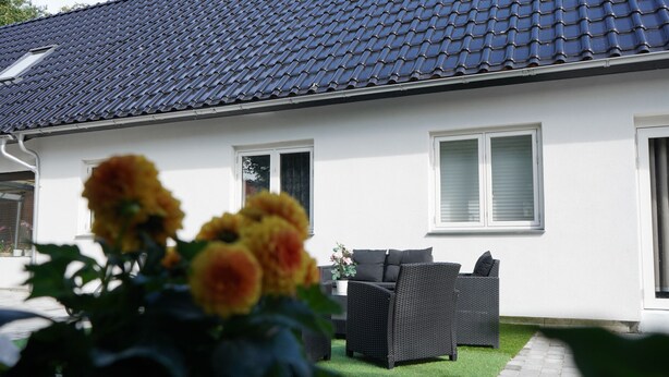 A house with a tiled roof, white exterior walls, and a small garden with outdoor furniture. - Stay Home Villa (Rødovre)
