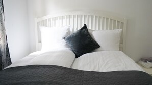 A white bed with a dark quilt, white pillows, and a dark throw blanket. - Stay Home Villa (Rødovre)