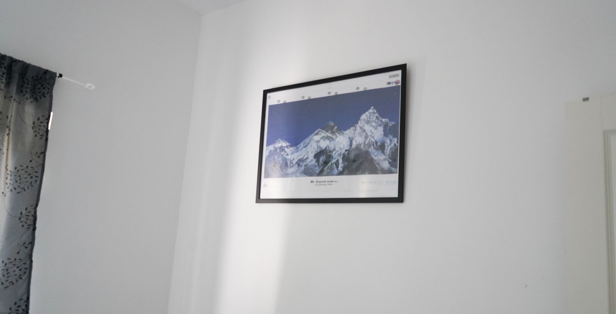 A framed picture of a mountain on a white wall.