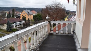 Een balkon met een balustrade met uitzicht op een stad met gebouwen en bomen.