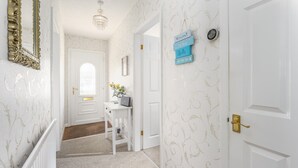 A hallway with a white door, a small table with a laptop, and a welcome sign on the wall. - Arkle House - a cosy home-from-home in Amble-by-the-Sea (Amble)