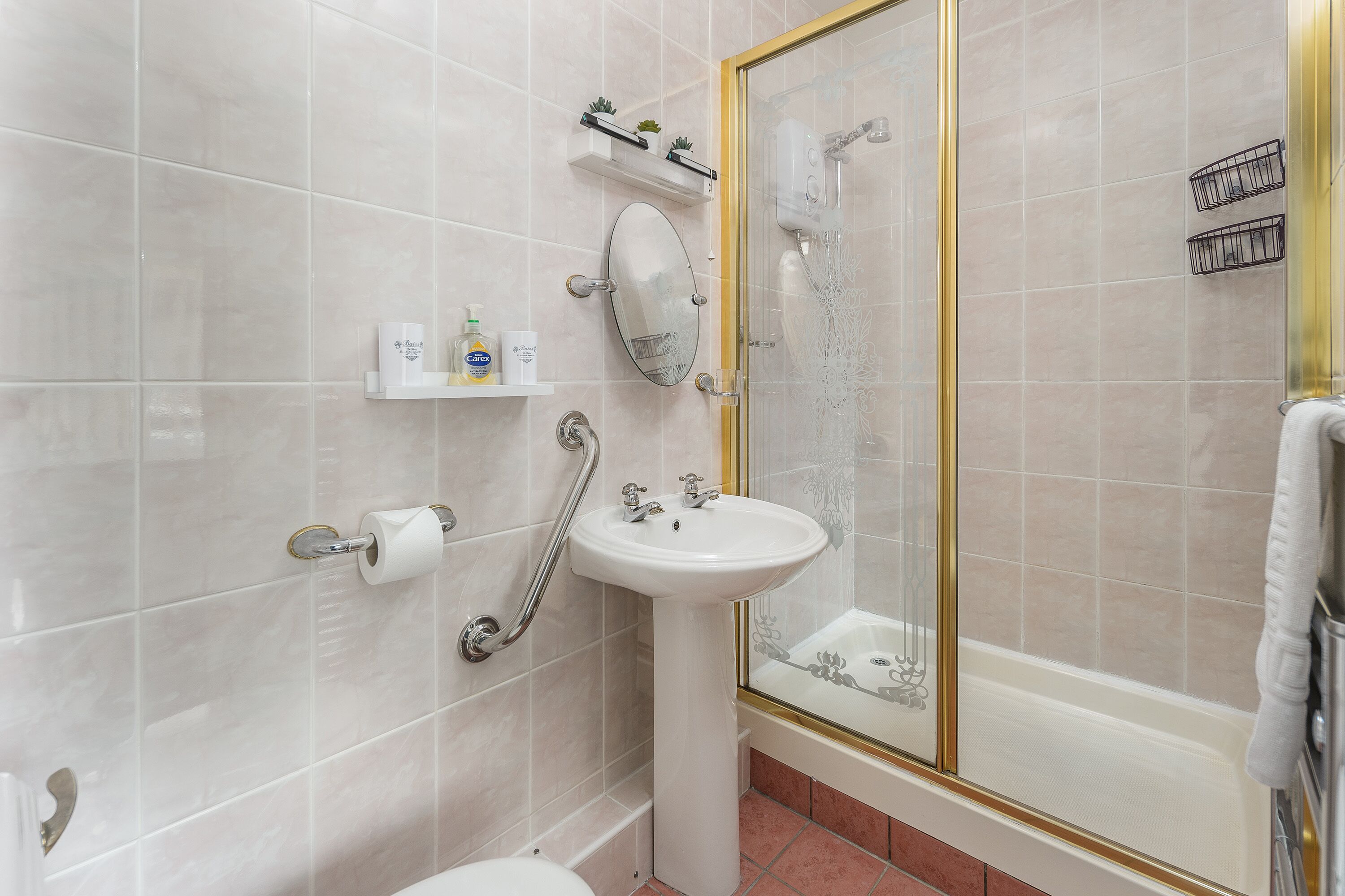 A bathroom with a white sink, toilet, and glass-enclosed shower.