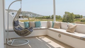 Un balcón con una silla colgante, asientos acolchados y vistas al paisaje.