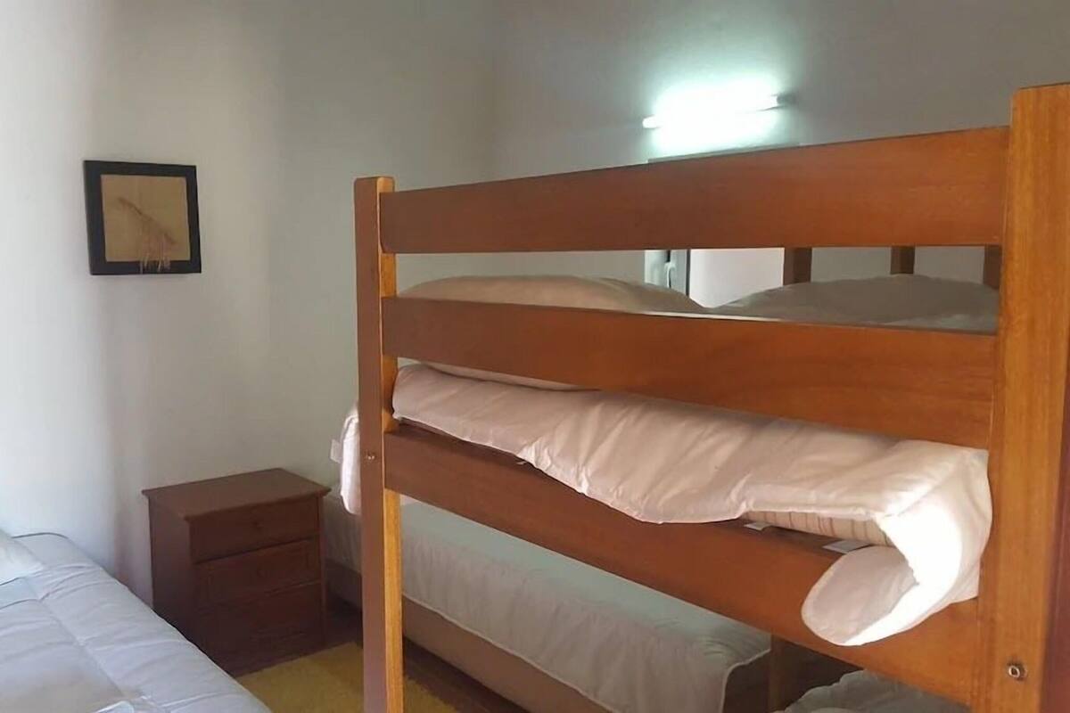 Una cama individual con estructura de madera, una mesita de noche y un cuadro colgado en la pared.