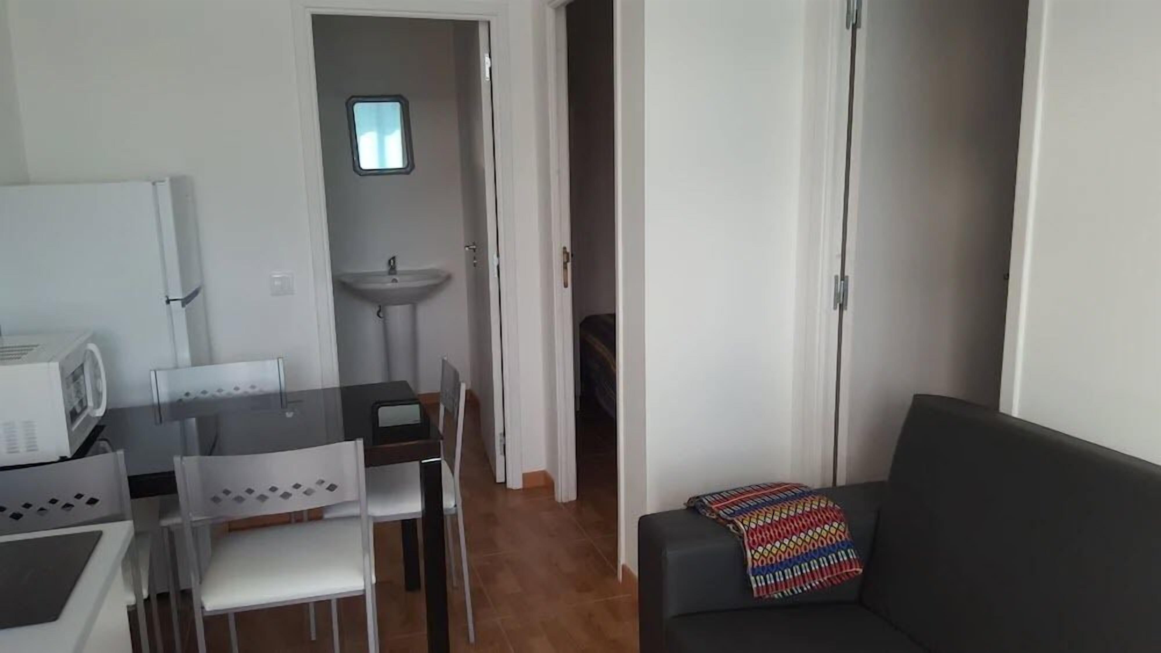 A compact living space with a kitchenette, a dining area, and a sofa.