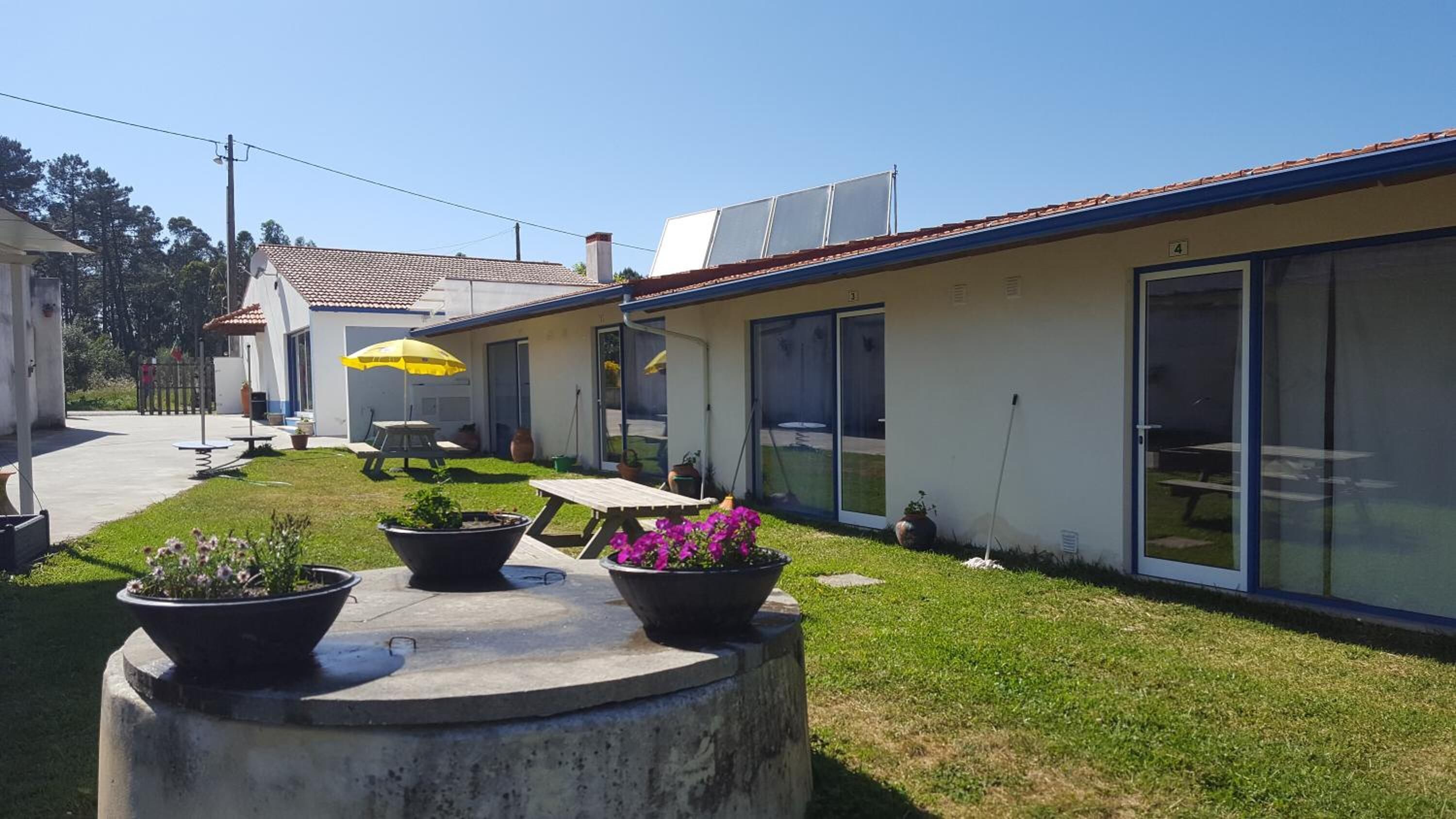 Ein modernes Gebäude mit einer Terrasse, die mit Blumentöpfen und Gartenmöbeln ausgestattet ist.