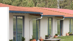 A modern building with a red roof, large glass windows, and a picnic table in the front. - Quinta do Valão (Alcobaça)