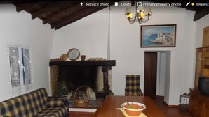 Ein Wohnzimmer mit Sofa, Kamin, Fernseher und einem Gemälde an der Wand.