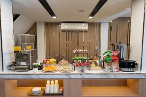 A breakfast buffet with various food items, a coffee machine, and a rice cooker. - Malades House (Bangkok)