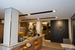 A modern hotel lobby with a reception desk, a coffee station, and a seating area. - Malades House (Bangkok)