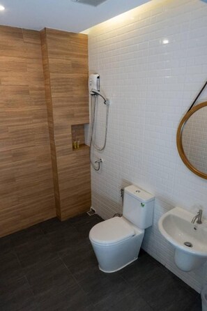 A modern bathroom with a wooden shower enclosure, a white toilet, and a sink with a mirror. - Malades House (Bangkok)