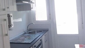 A compact kitchen with white cabinets, a stainless steel sink, and a built-in oven.