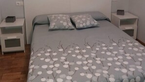 A bedroom with a bed, two nightstands, and a wall decoration of dandelions.