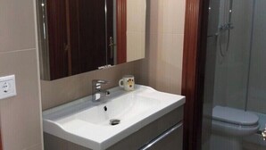 A bathroom with a white sink, a mirror, and a shower.