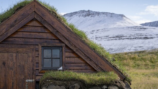 A wooden cabin with a stone wall foundation, a door, and a window. - Fisherman Hótel Suðureyri (Sudureyri)