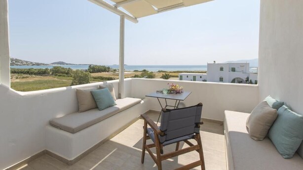 A balcony with a white sofa, a wooden chair, and a small table with flowers. - Villa Lantana with Private Swimming Pool - Salinus Naxian Villas (Naxos)