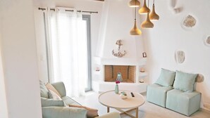 A modern living room with a fireplace, light-colored sofas, and pendant lighting. - Villa Lantana with Private Swimming Pool - Salinus Naxian Villas (Naxos)
