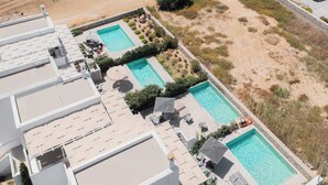 An aerial view of a hotel with two rectangular swimming pools, lounge chairs, and a landscaped garden area. - Villa Lantana with Private Swimming Pool - Salinus Naxian Villas (Naxos)