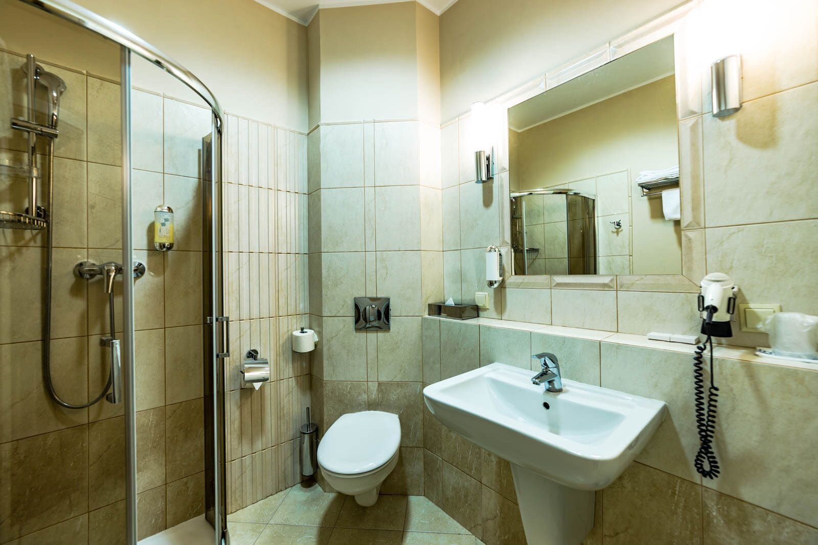 Une salle de bain équipée d’une douche, de toilettes, d’un lavabo et d’un miroir avec un téléphone.