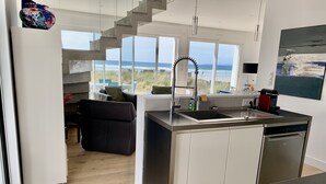 Eine moderne Küche mit Meerblick, eine Treppe und ein Essbereich mit Blick aufs Meer.