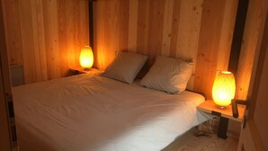 A wooden room with a bed, two nightstands, and two lamps. - the shepherd's chalet. (Ventron)