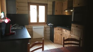 A kitchen with wooden cabinets, a window, a sink, and a stove. - the shepherd's chalet. (Ventron)