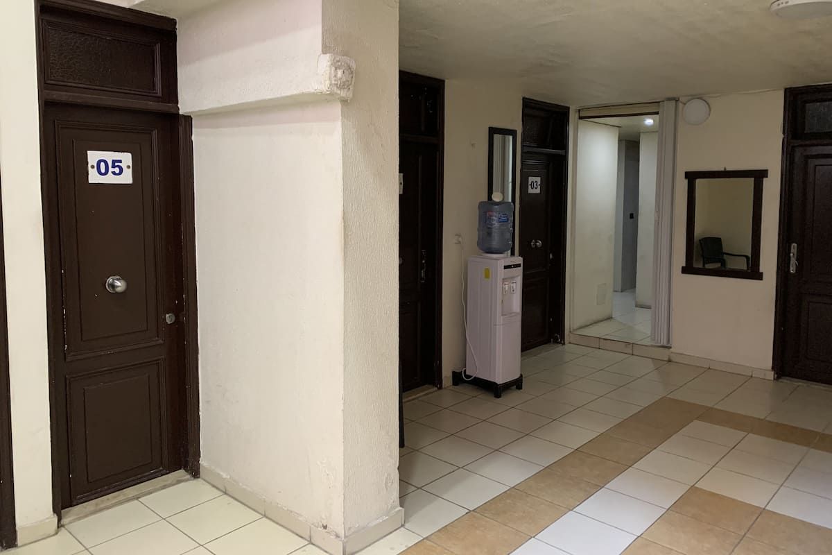 A hallway with a water dispenser, a mirror, and doors numbered 03 and 05.