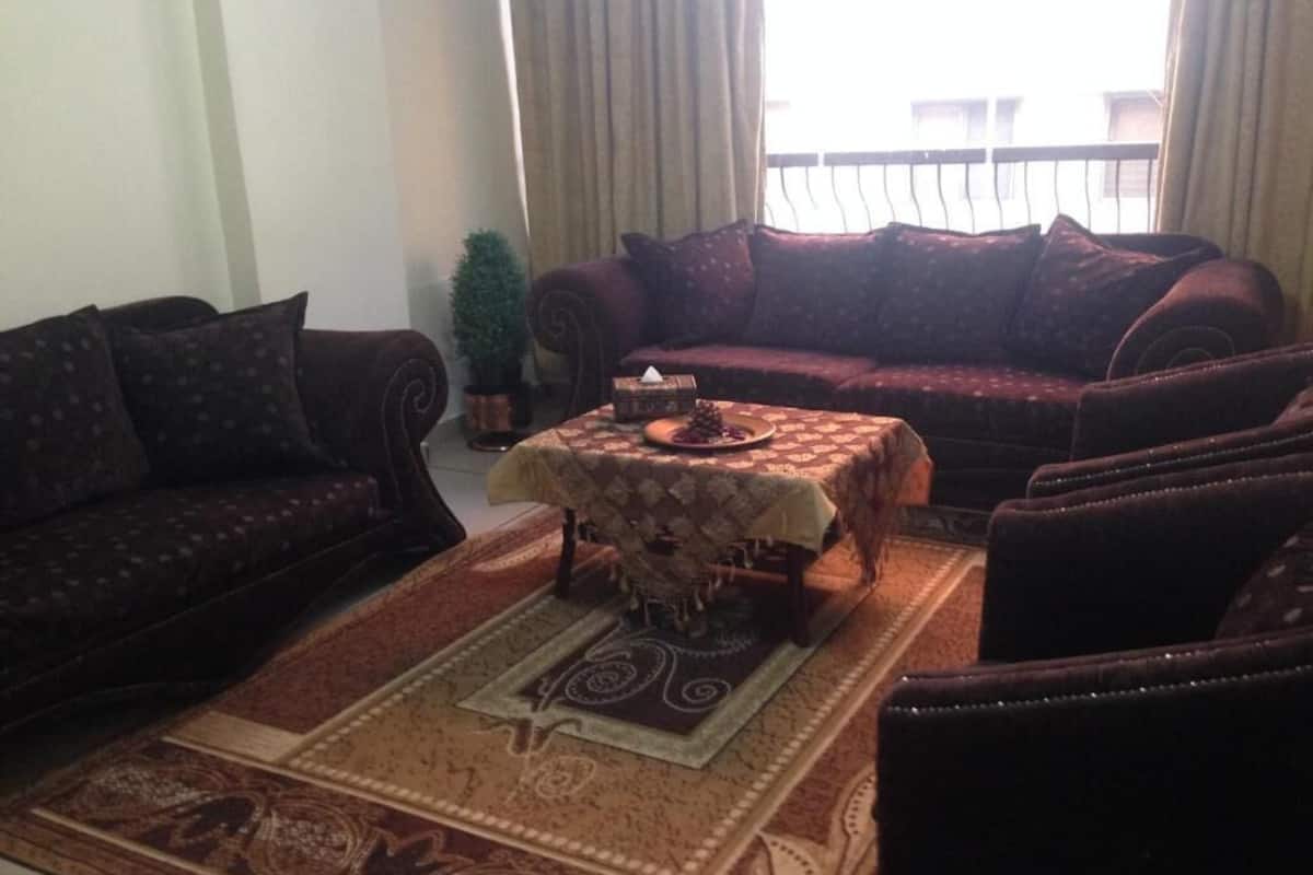A living room with a sofa set, a coffee table, and a patterned rug.