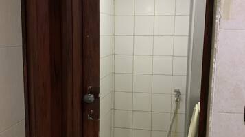 A small, tiled bathroom with a toilet and a shower stall.