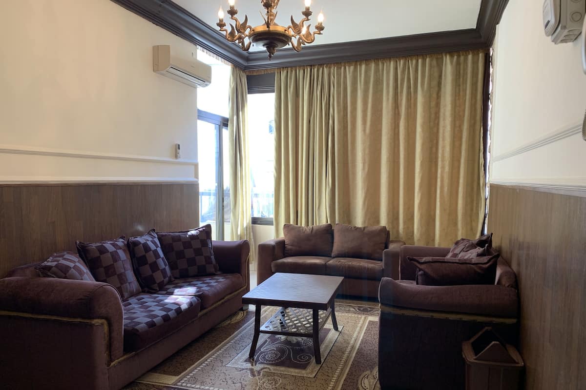 A living room with two sofas, a coffee table, and a patterned rug.