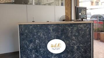 A reception desk with a marble top, a logo, and a computer monitor.
