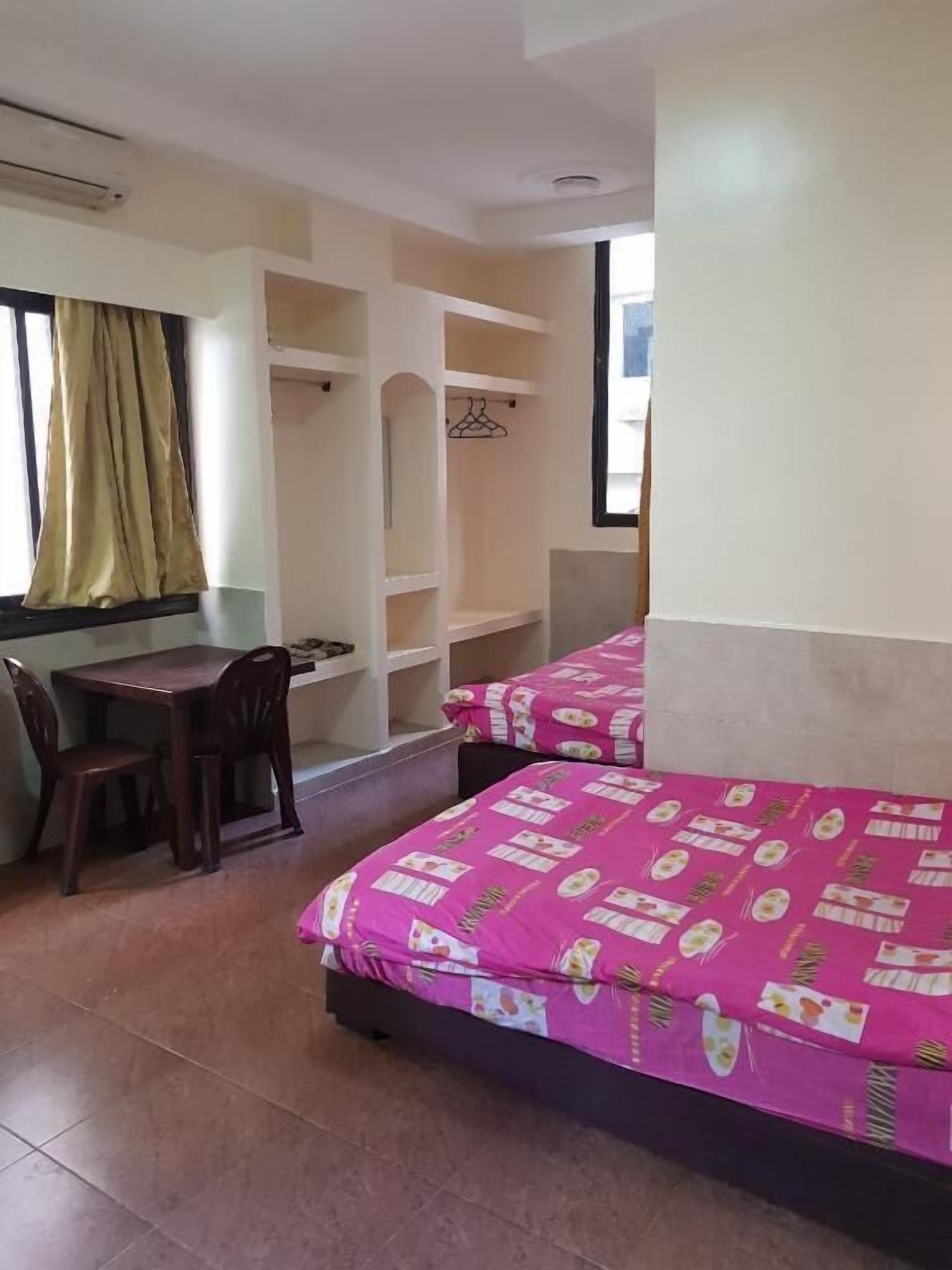 A room with two beds, a desk, and a chair.