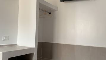 A small kitchenette with a refrigerator, a microwave, and a small shelf.