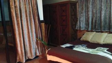 A bedroom with a bed, a wardrobe, and curtains.