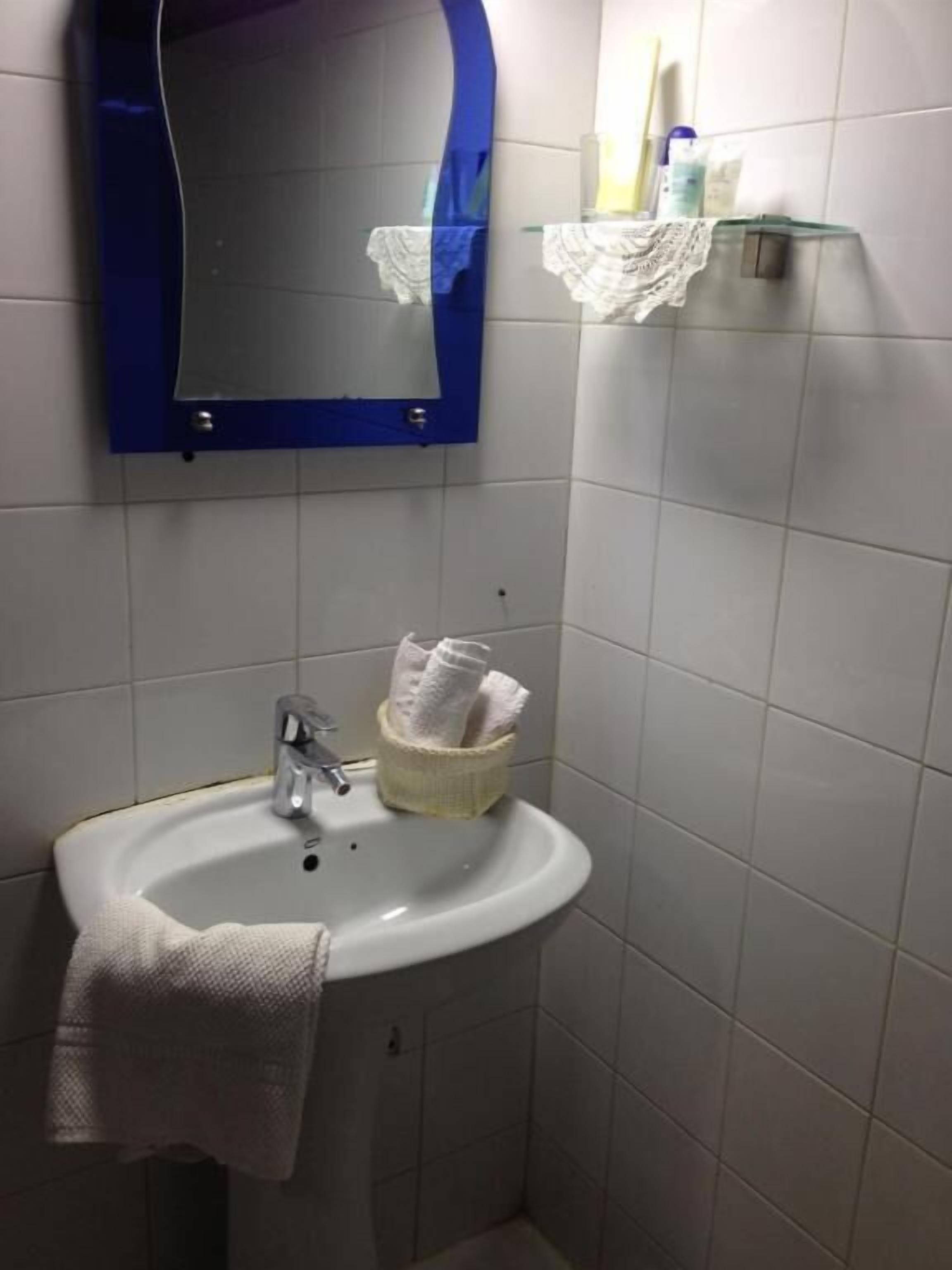 A bathroom with a white sink, a mirror, and a towel hanging on the wall.