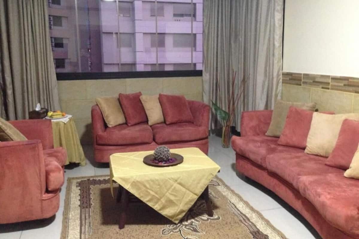 A living room with a red sofa set, a yellow table, and a view of buildings through a window.