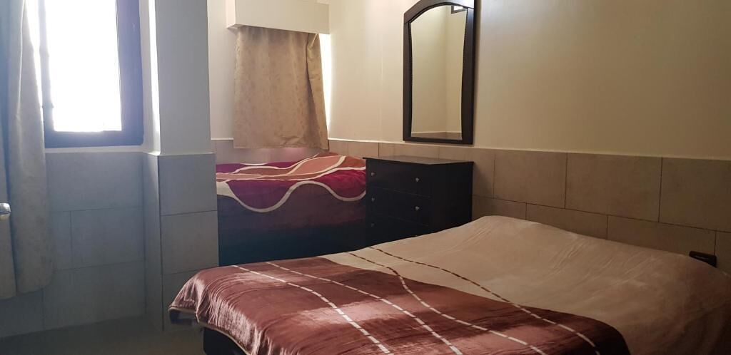 A hotel room with a bed, a dresser, a mirror, and a window with curtains.