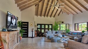 A spacious living room with a high ceiling, a television, sofas, and a coffee table.